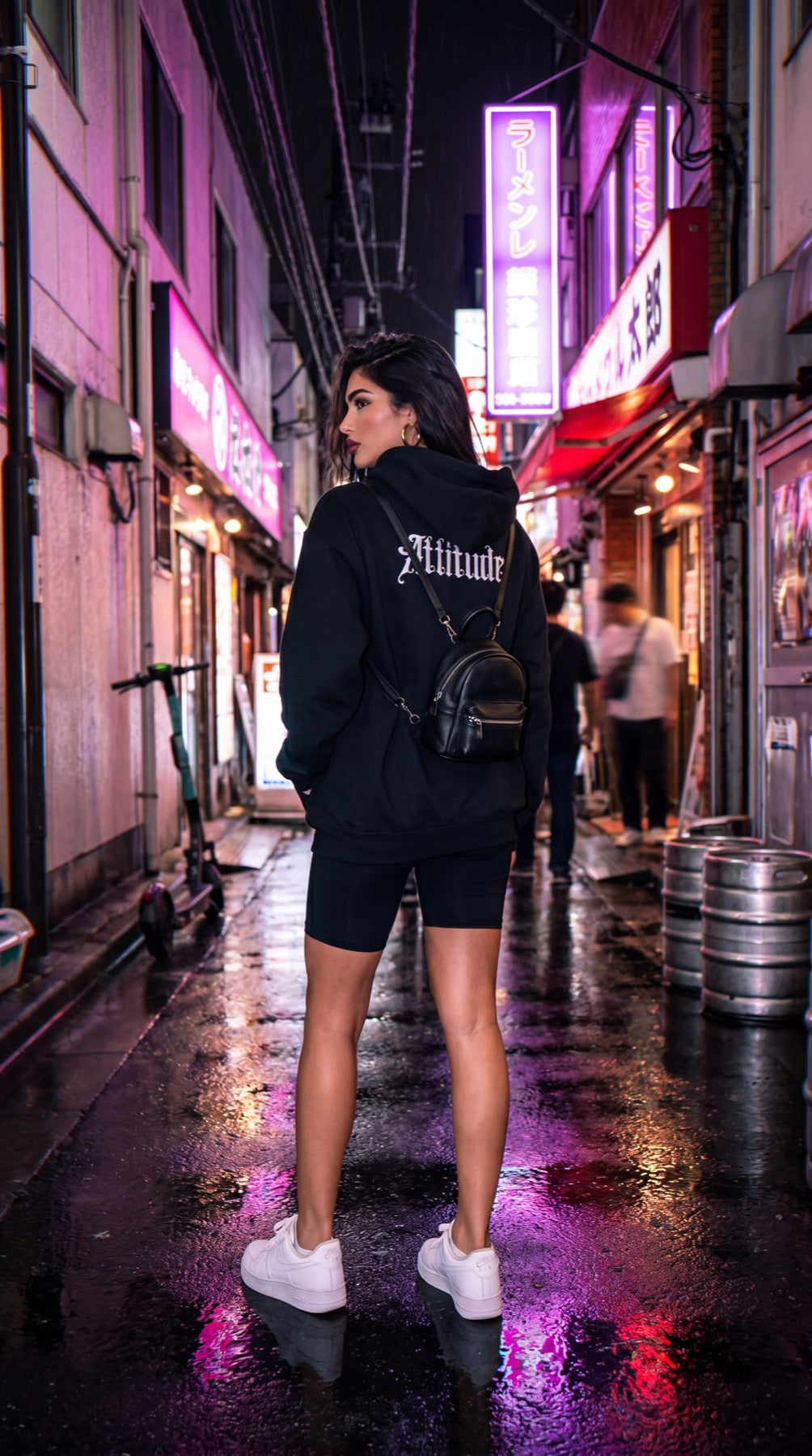 Hoodie Attitude noir dans les rues de Tokyo sous la pluie, néons urbains